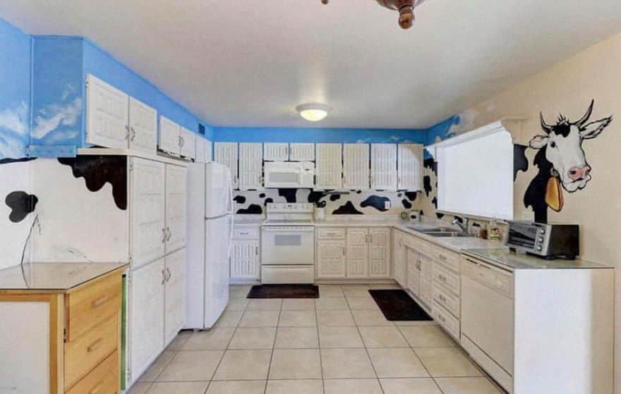 a kitchen with a very strange and long painting of a cow on the wall