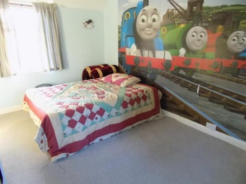 a bedroom with an unsettling mural of thomas the tank engine on the wall