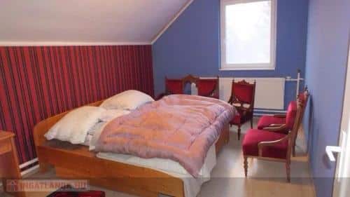 a bedroom with a bed surrounded by five red velvet chairs