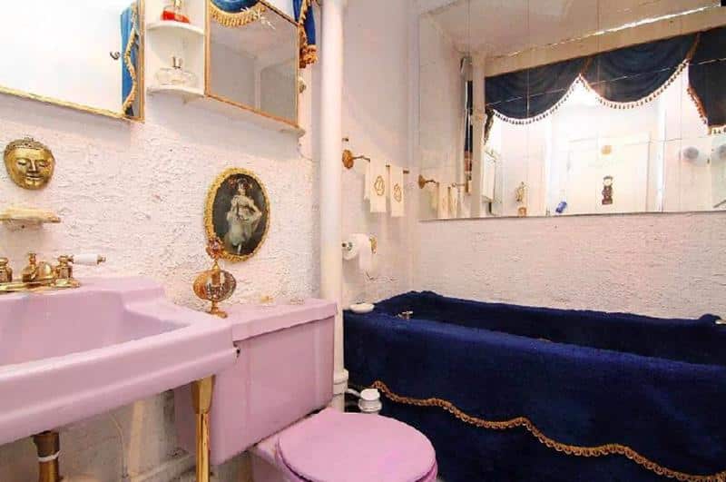 a basement bathroom with a velvet covered tub and strangely regal decorations