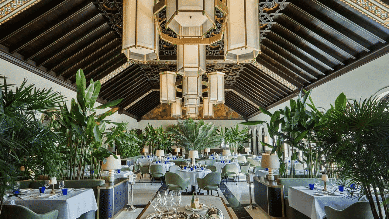 a beautifully appointed restaurant in high-Florida style with palm trees and white table cloths.