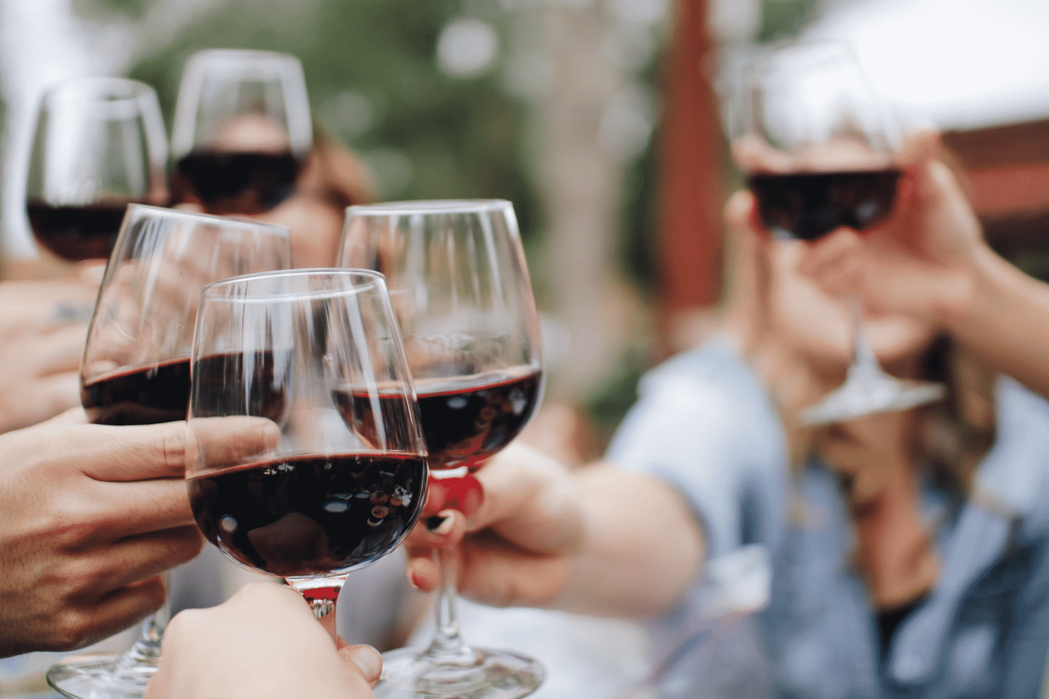 a group of wine glasses being held up in a toast.