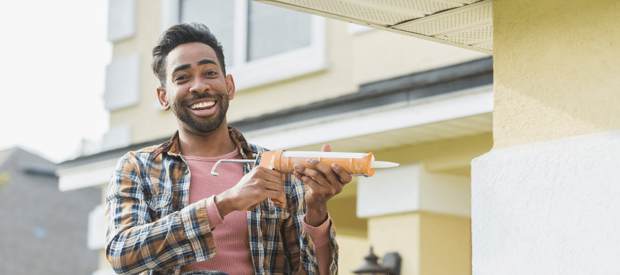 man smiling while holding a silicon adhesive tools