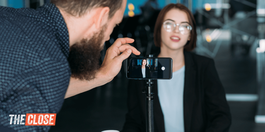 Real estate agent sitting in front of smartphone on tripod to record social media video