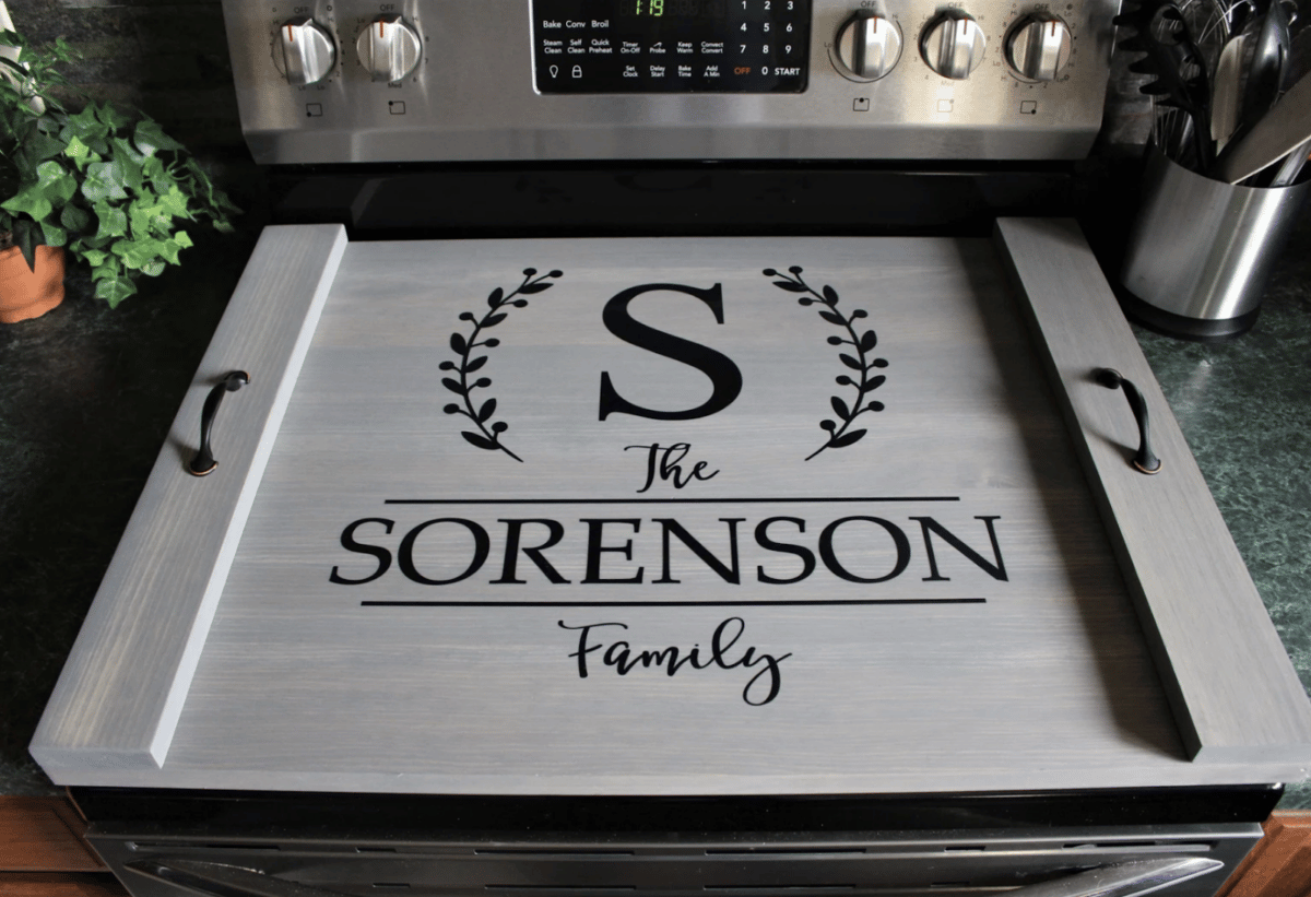 A wooden noodle board sitting on a stovetop with a family name painted on it