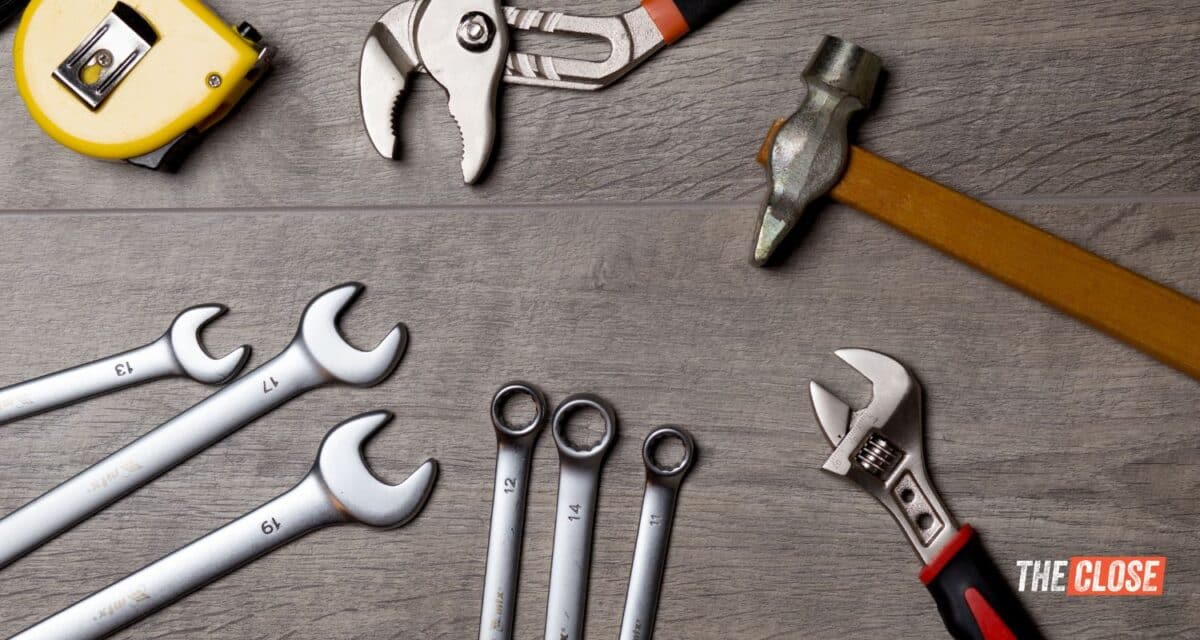 a variety of tools laying out on a grey wood background with Real Tactics Pro's logo in the lower right hand corner