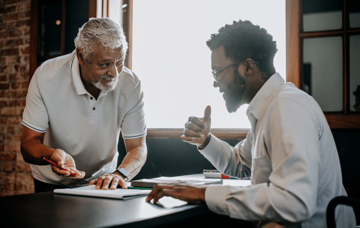 Image of older man showing something on paper to a younger man.