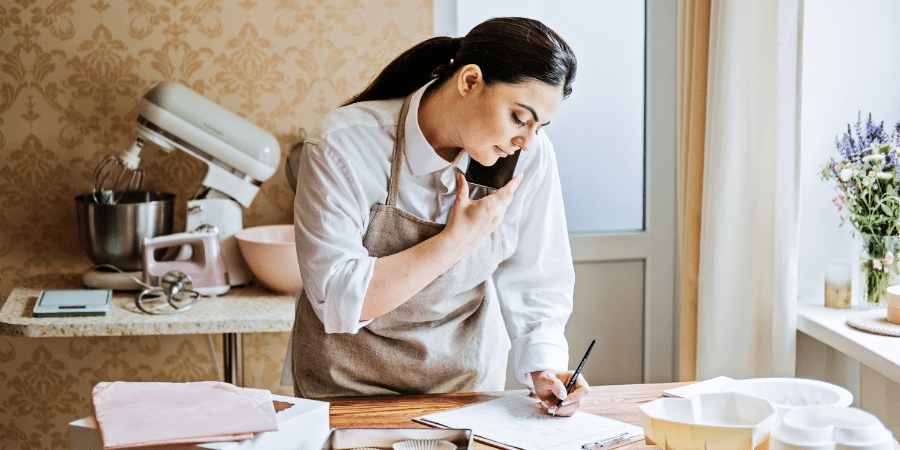 Woman in a bakery on the phone taking an order.